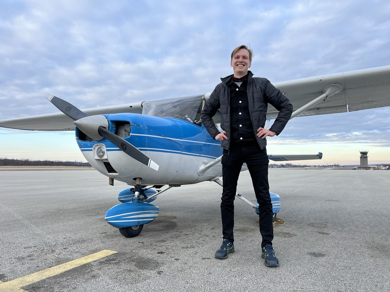 Daniil Dumanskii standing next to a blue and white training aircraft on airport tarmac
