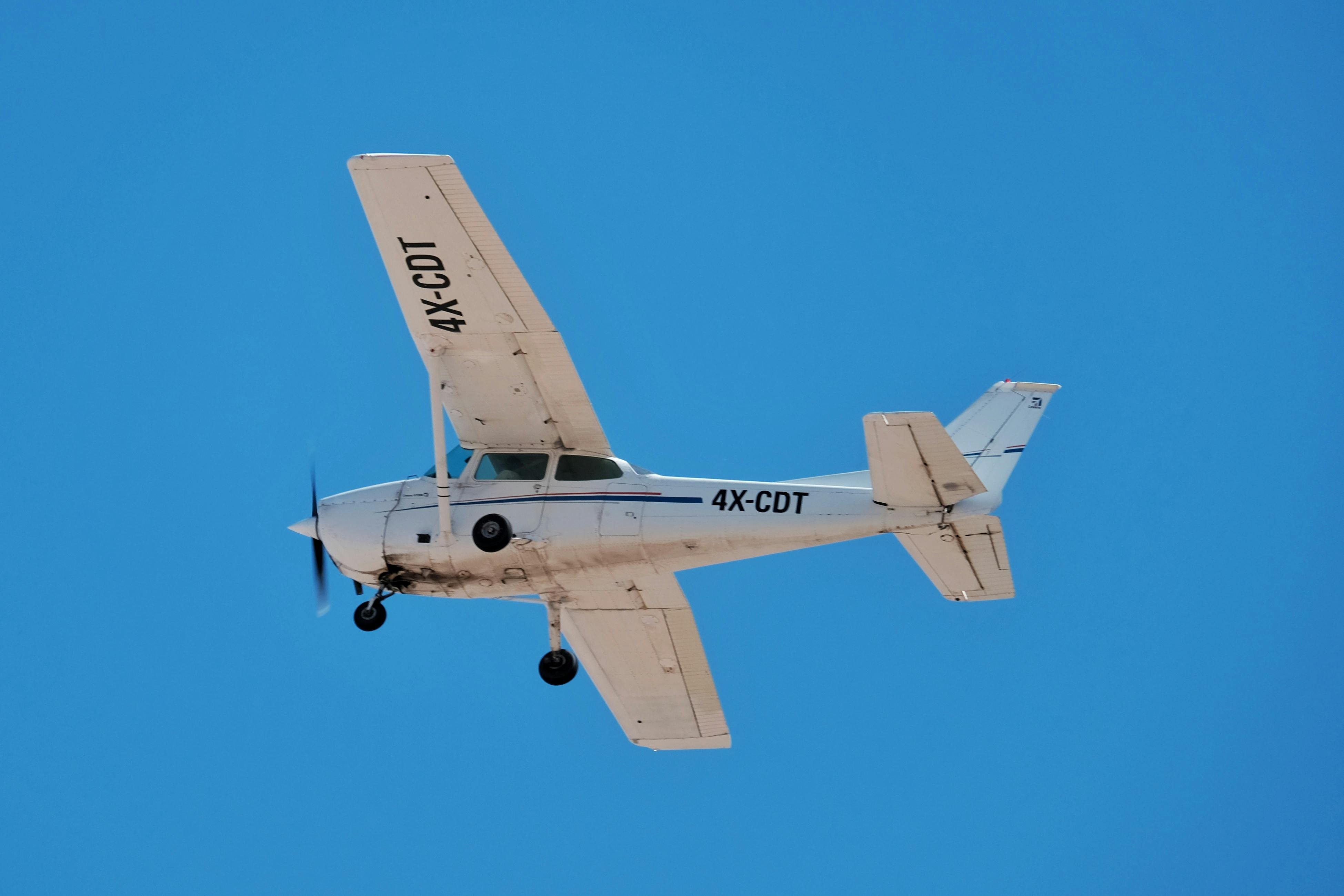White training aircraft flying against clear blue sky - Dumanskii Aviation flight training